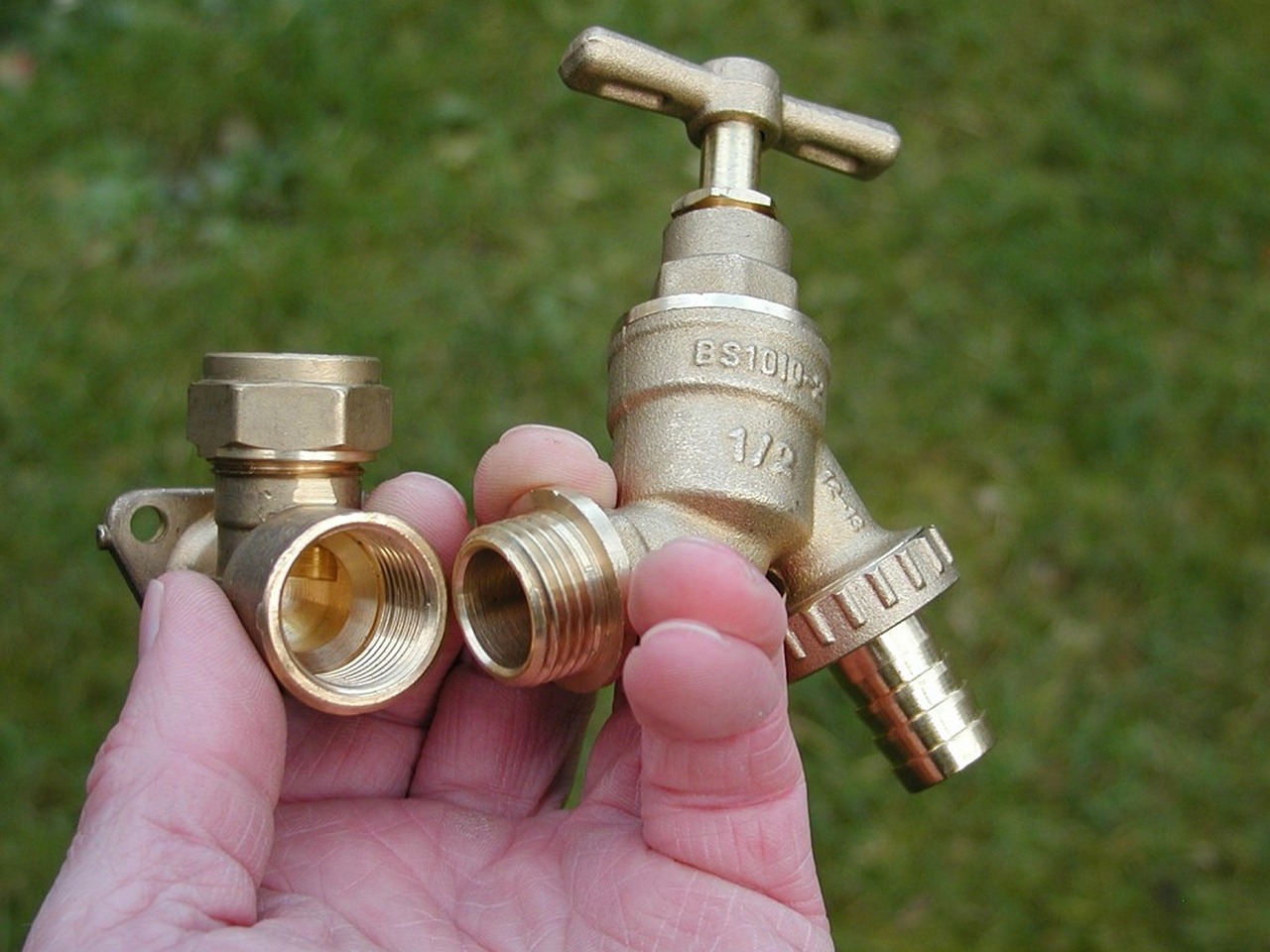 Hand holding brass tap and valve fittings